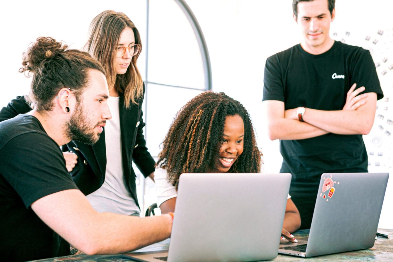 A group of people sitting around a table looking at a laptop.