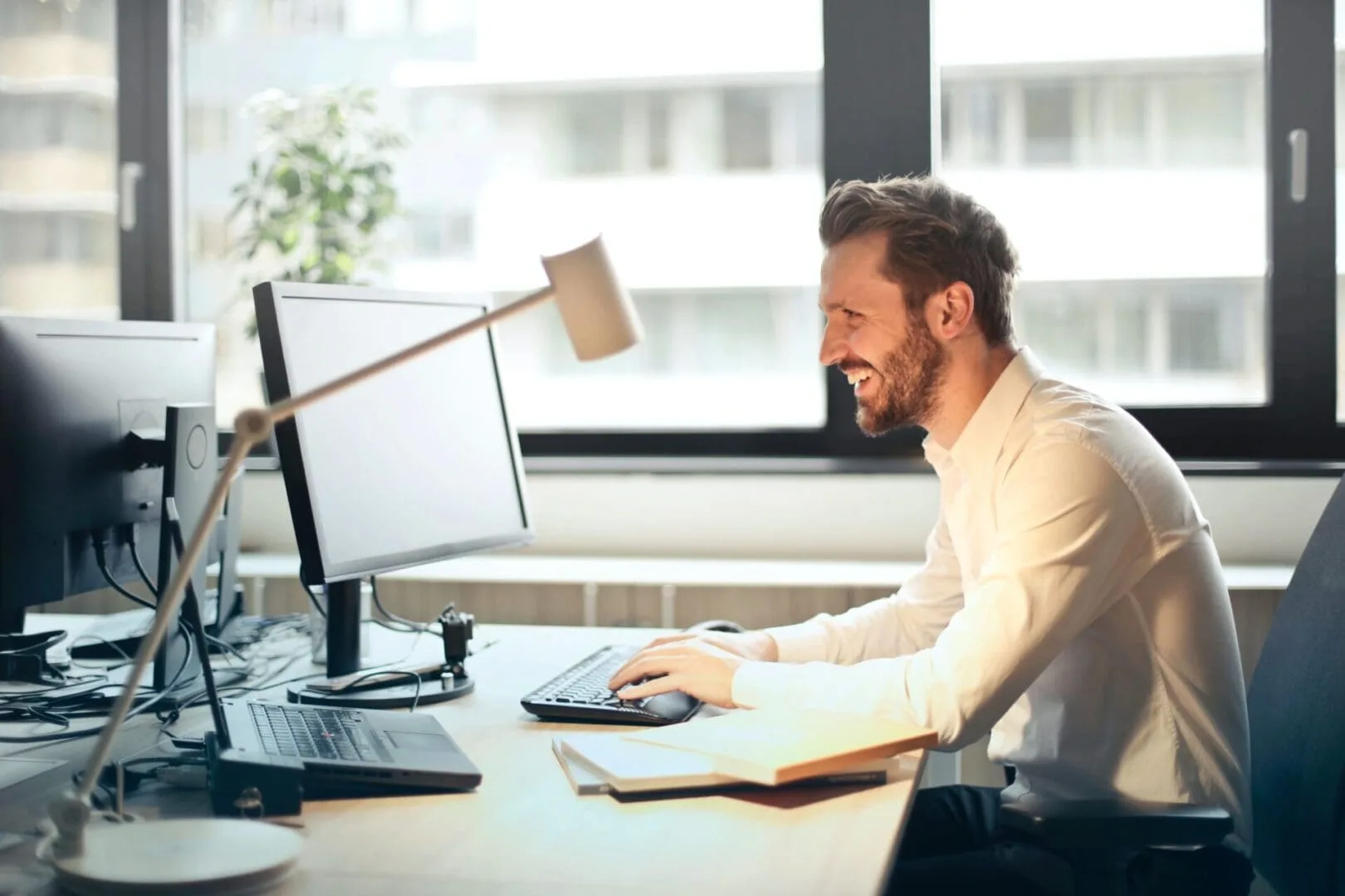 A man sitting at his desk with a laptop and computer.