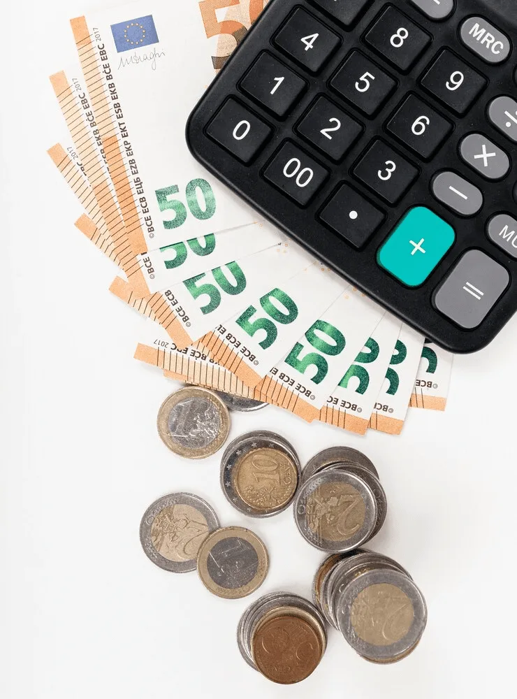 A calculator and some money on top of the table.