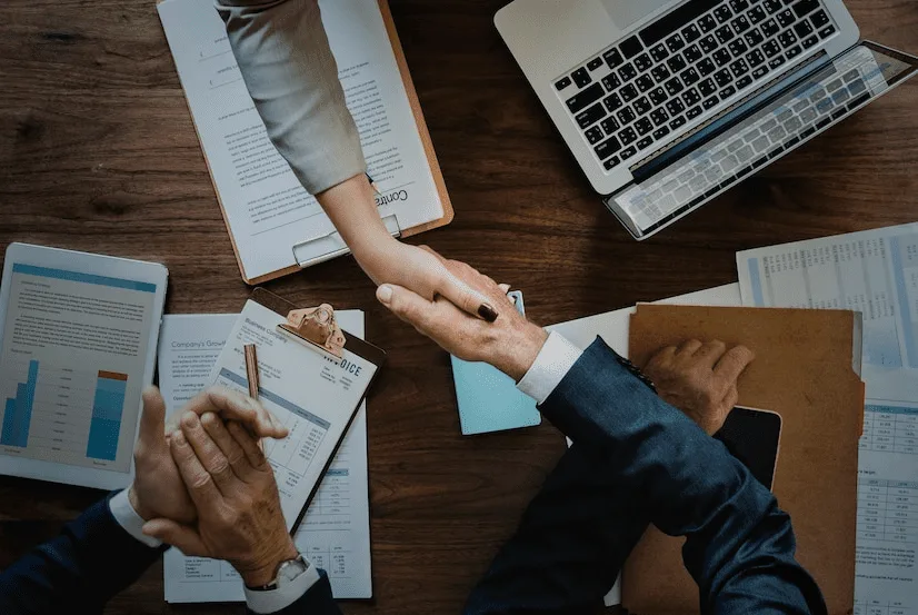 A group of people sitting around a table shaking hands.