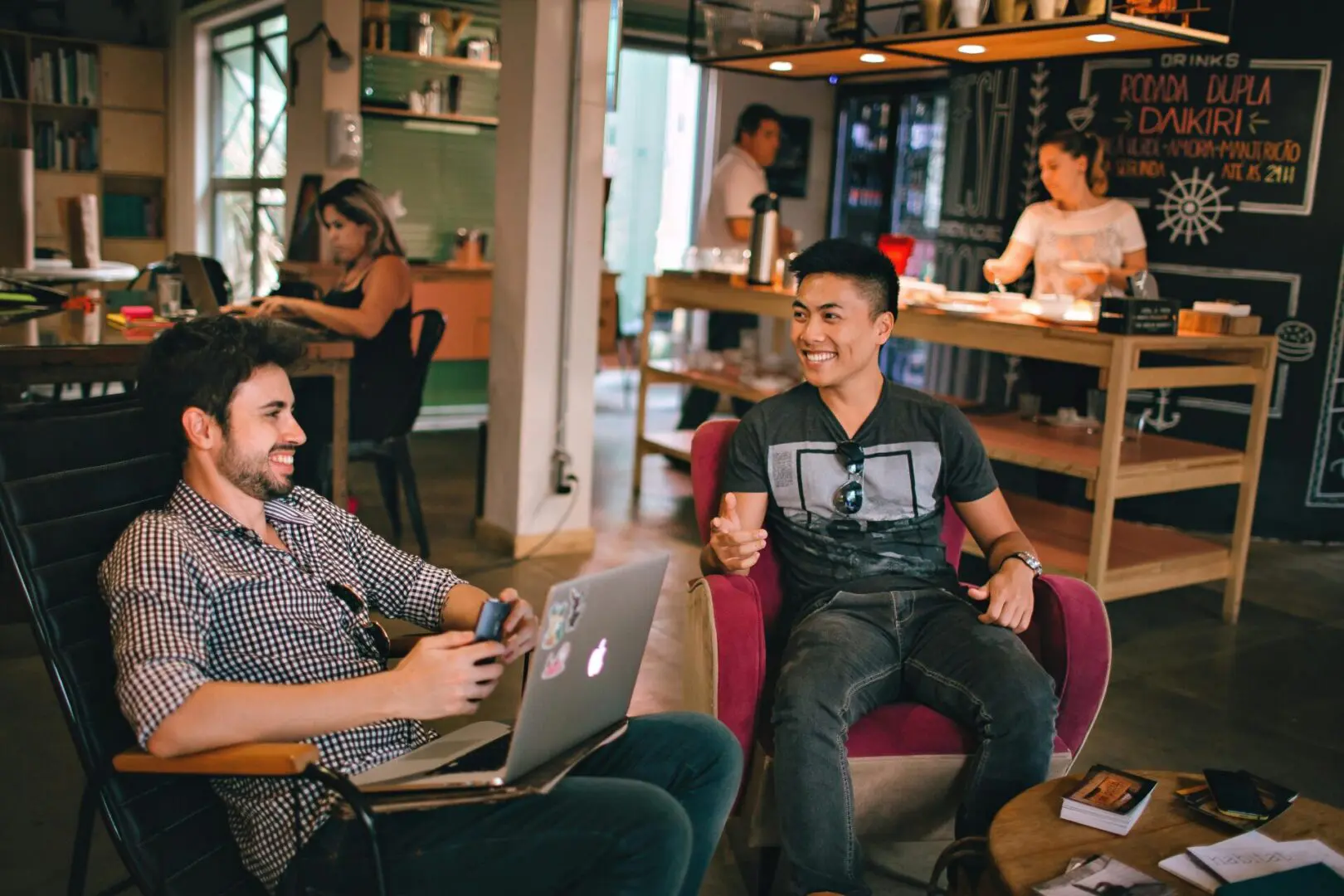 Two men sitting in a room with laptops.