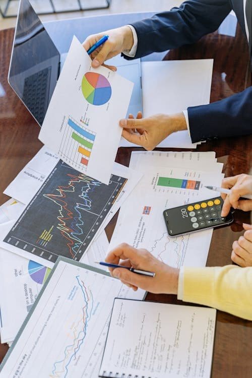 Papers and documents on a desk being reviewed for determining business loan needs.