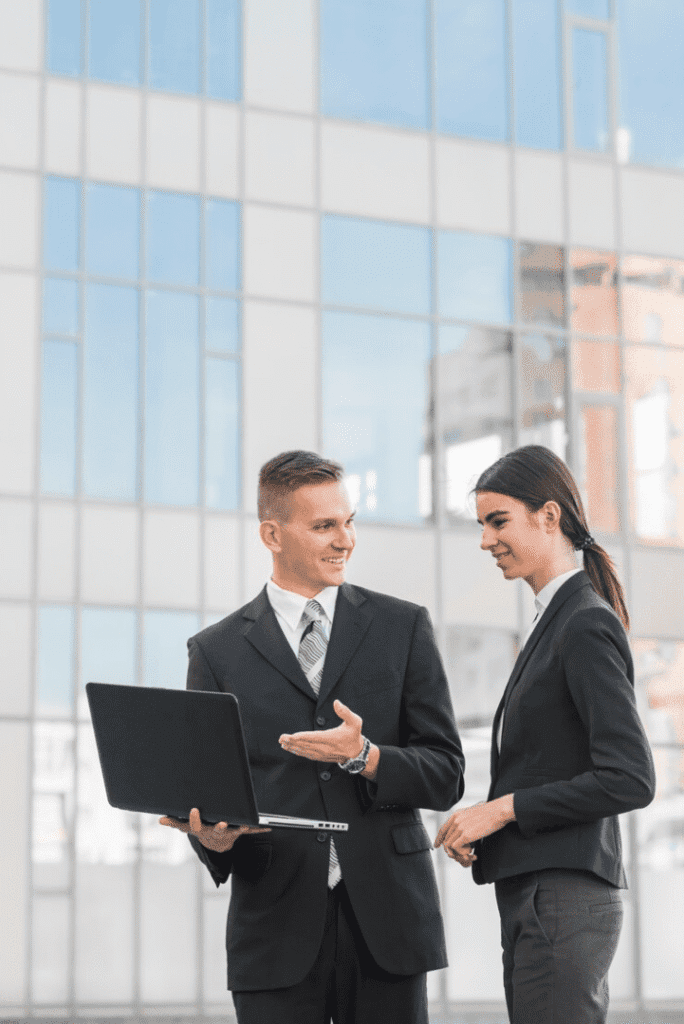 Two people in suits are looking at a laptop.
