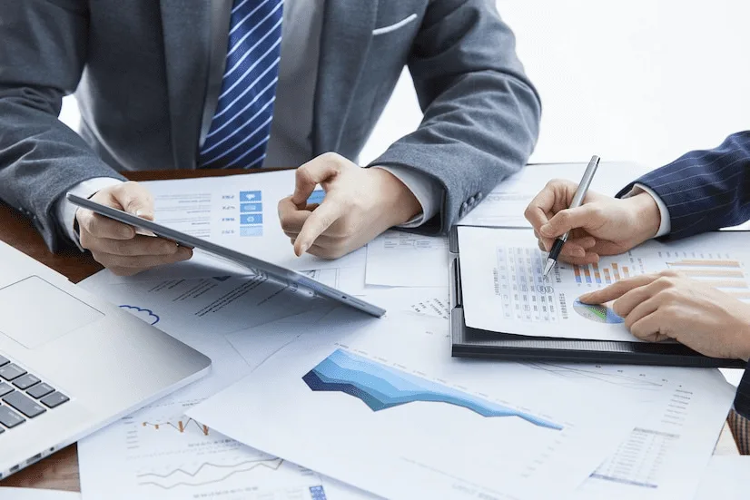 Two people sitting at a table with papers and a laptop