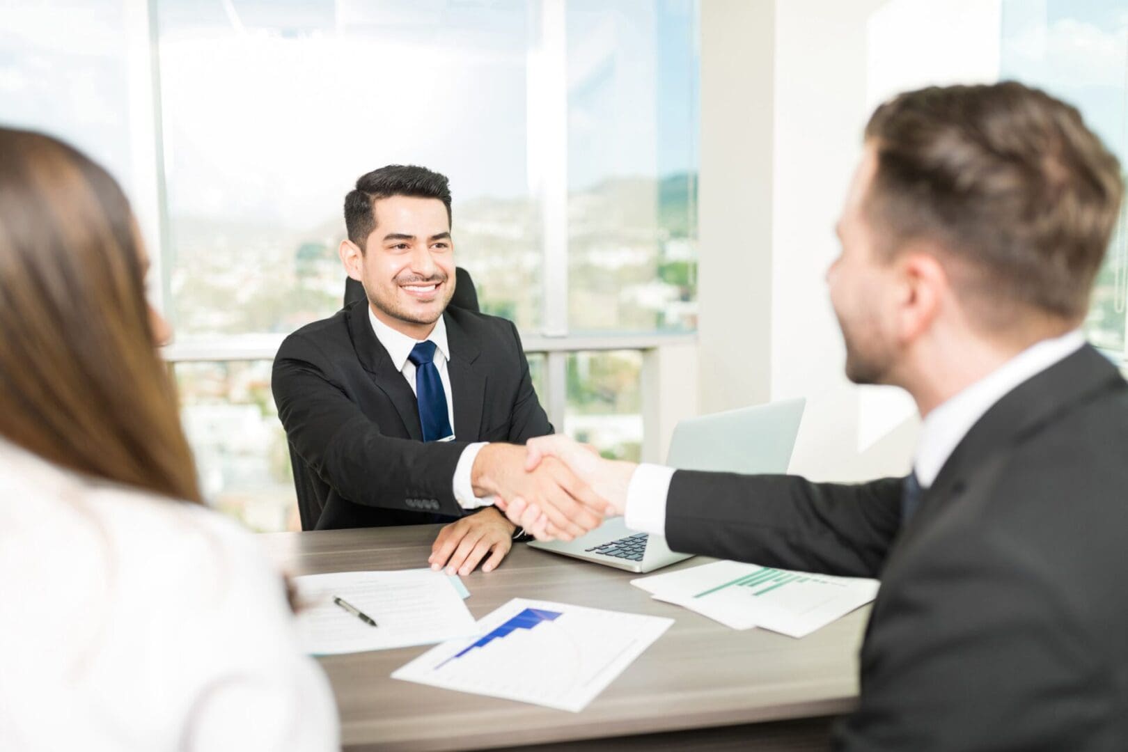 A man shaking hands with another man in front of two other men.