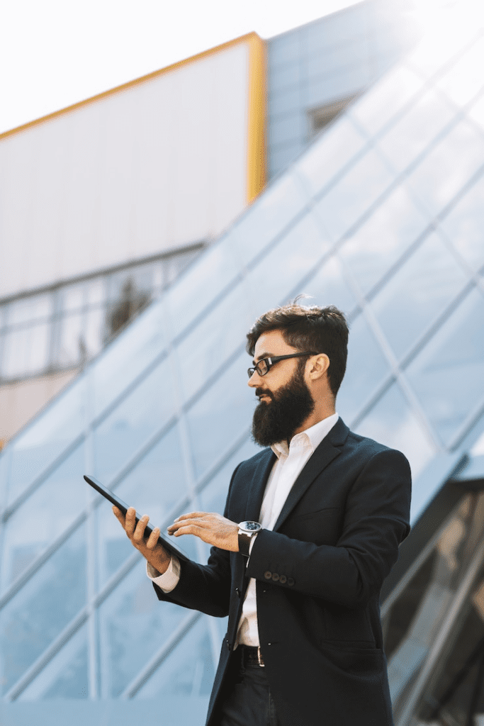 A man with a beard and glasses is holding a tablet