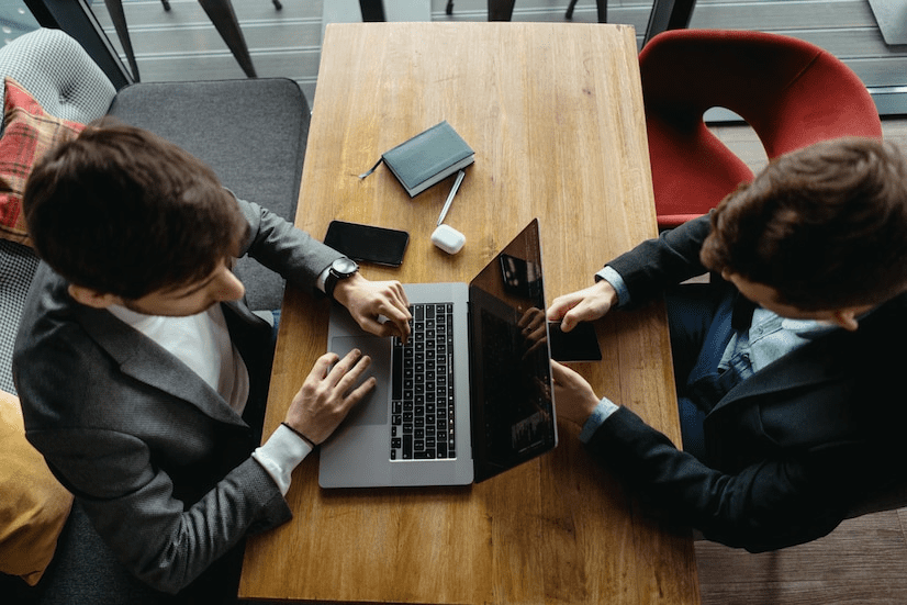 Two people sitting at a table with laptops