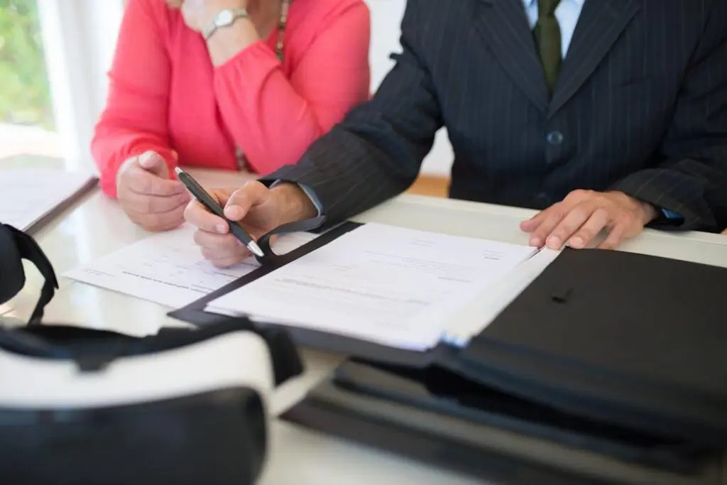 Person holding a pen and signing a document on a piece of paper