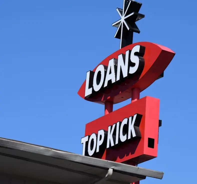 This picture shows a red sign board having ‘loans’ written on it.