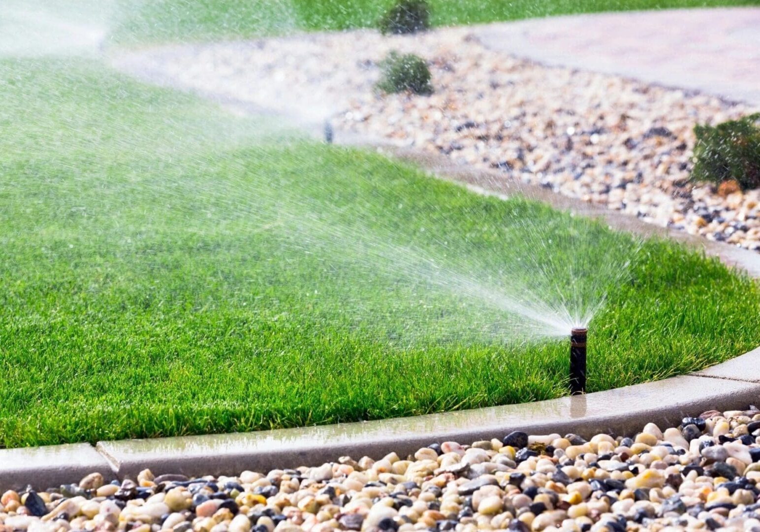 A lawn sprinkled with water and is being watered.