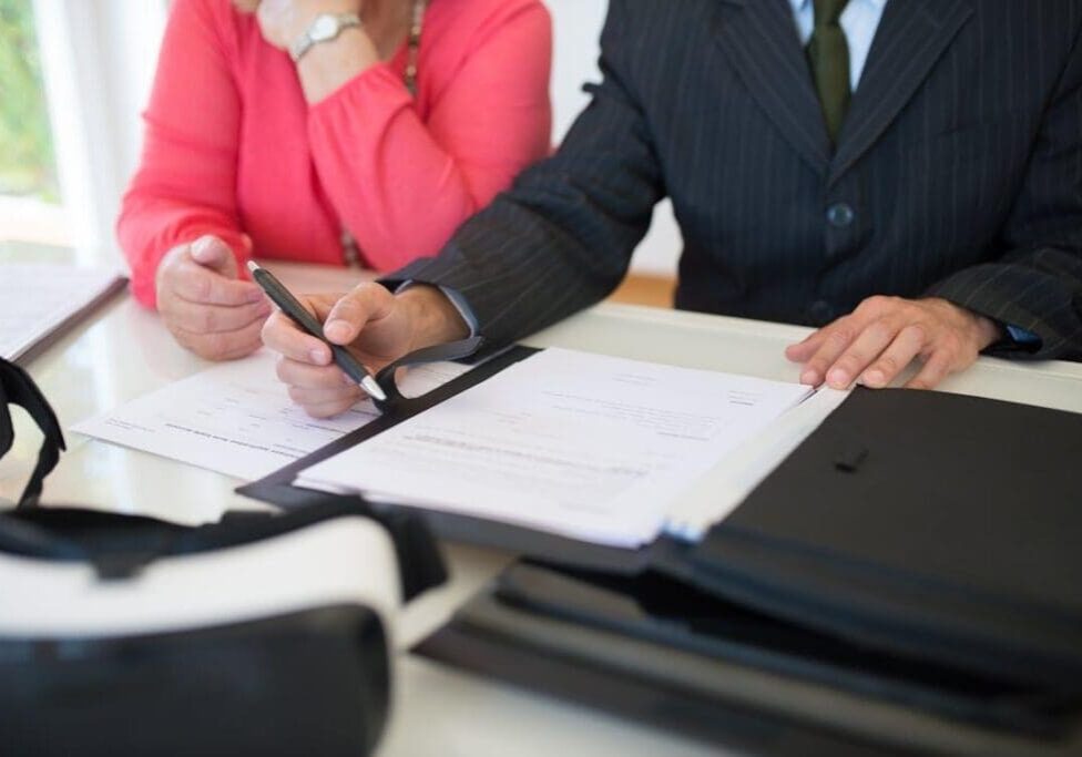 Person holding a pen and signing a document on a piece of paper