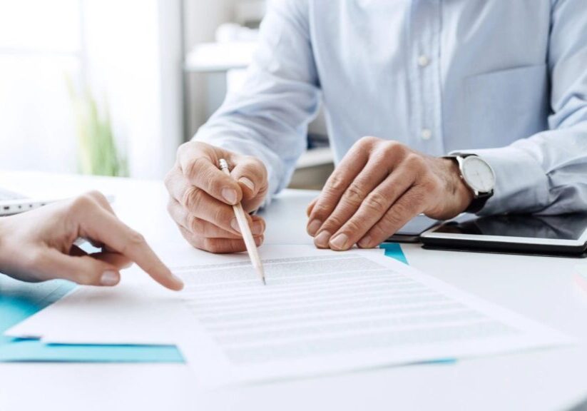 Two people are sitting at a table and one is holding a pencil