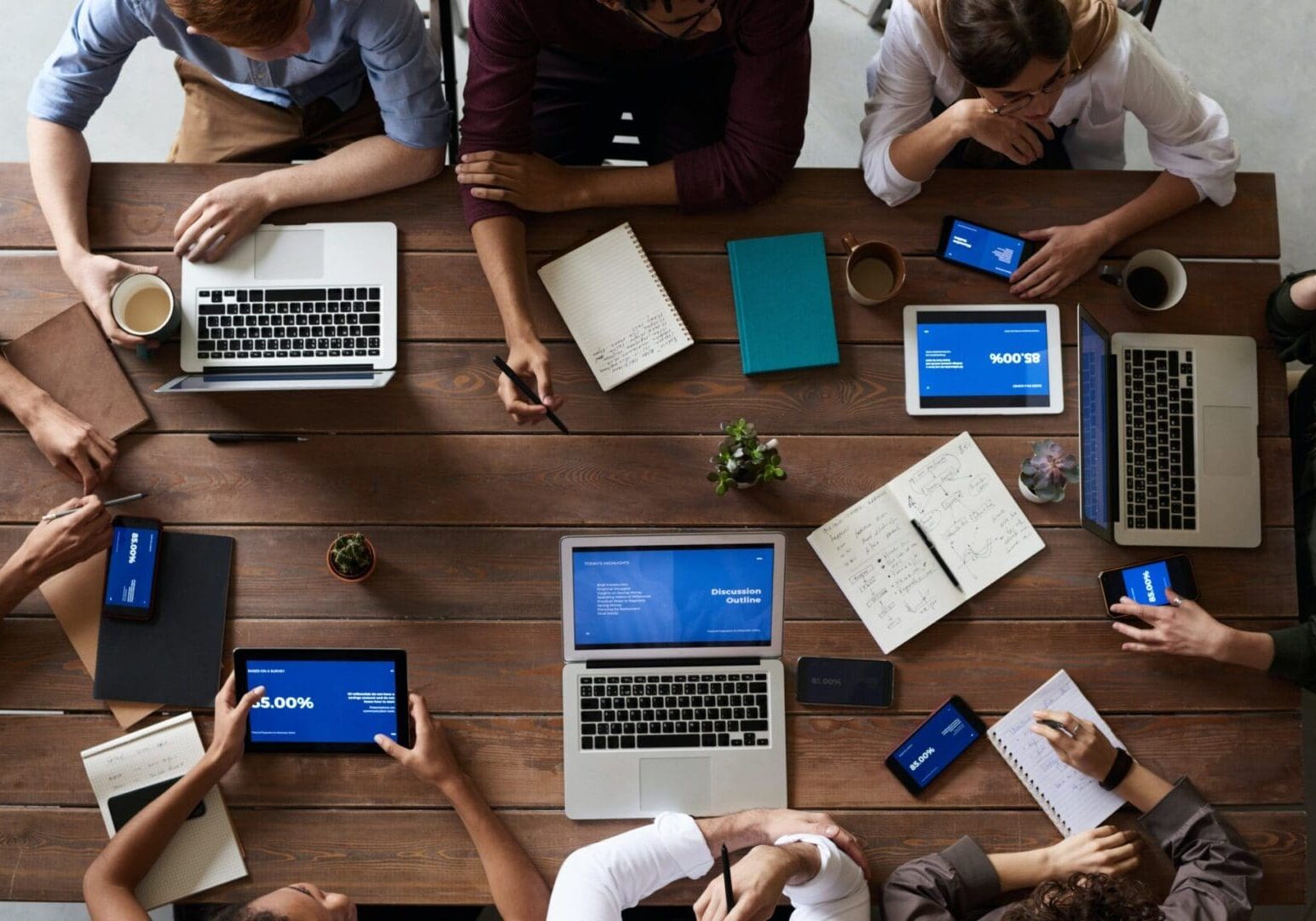 A group of people sitting around a table with laptops.